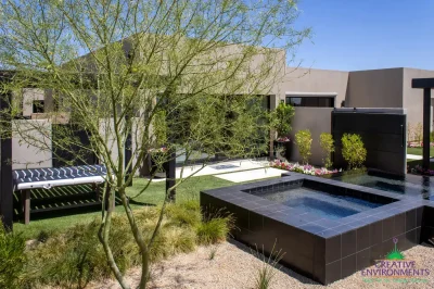Custom backyard design with raised black spa, real grass and organized planting.