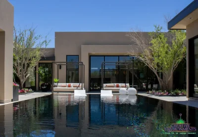 Custom backyard design with cabanas, black pool and organized planting.