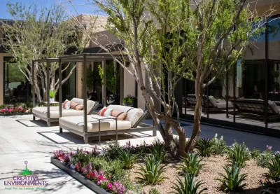 Custom backyard design with cabanas, organized planting and tree.