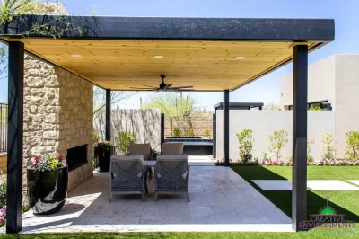 Custom backyard design with metal shade structure, natural stone fireplace and artificial turf.