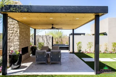 Custom backyard design with metal shade structure, natural stone fireplace and artificial turf.