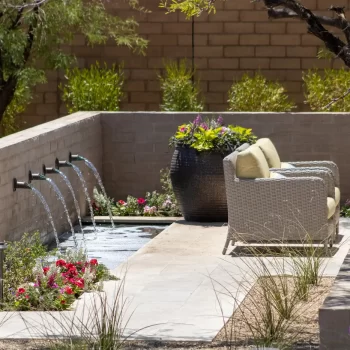 Custom backyard design with metal scupper water feature, large planter and fire table.