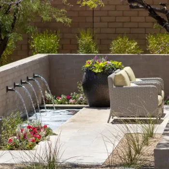 Custom backyard design with metal scupper water feature, large planter and fire table.