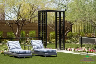Custom backyard design with organized planting, metal archway and metal fencing.